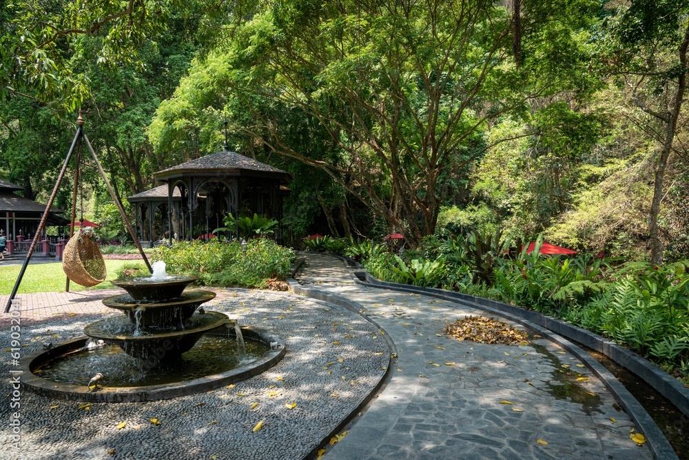 Poster a patio with a fountain near a picnic bench with trees in the background