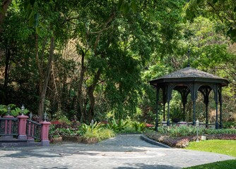 a gazebo in a garden with a stone path and lush green trees