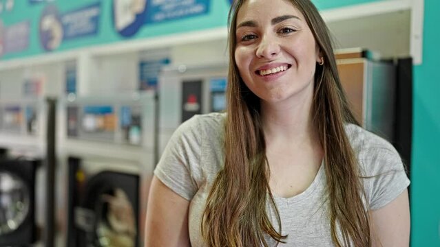 Young beautiful hispanic woman smiling confident standing at laundry room