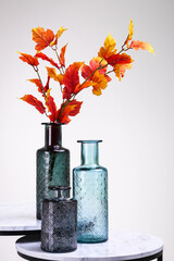 Three vases on a table with autumn leaves