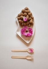 Pink rose petals with edible clay stones and a wooden fork and spoon flat lay