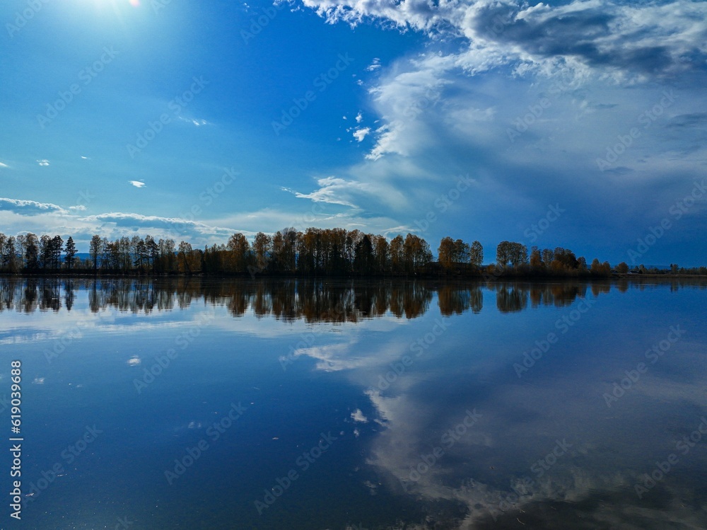 Sticker Tranquil outdoor scene featuring a body of water with a peaceful reflection of the sky and clouds.