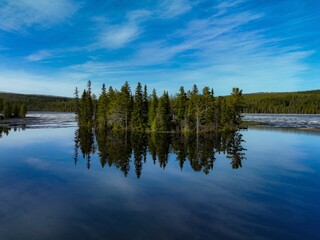 Tranquil lake landscape featuring a cluster of trees in the center of the water.