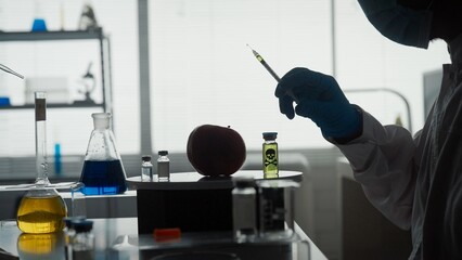 Dark silhouette of a male scientist with a syringe in his hand. A researcher is about to inject...