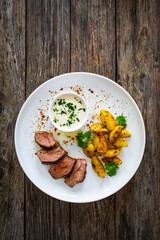 Grilled pork loin steaks with fried potatoes on wooden table