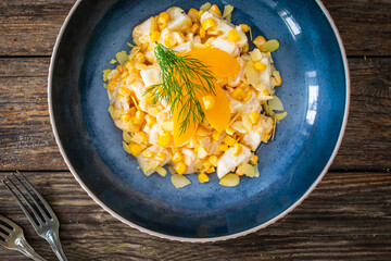 Fruit salad - peaches, pineapples, almonds and corn in mayonnaise on wooden table