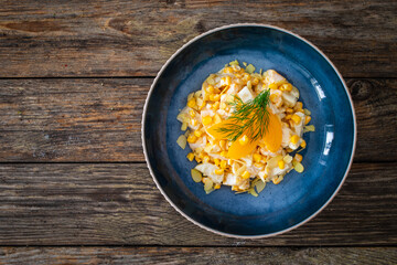 Fruit salad - peaches, pineapples, almonds and corn in mayonnaise on wooden table