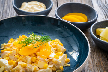 Fruit salad - peaches, pineapples, almonds and corn in mayonnaise on wooden table