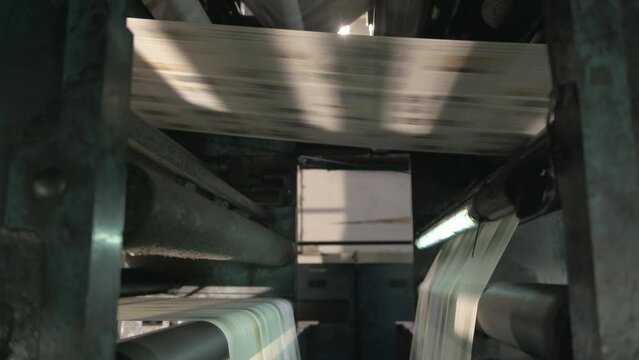 Newspapers rolling on printing press.
