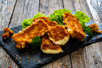 Breaded cheese sticks with lettuce and dressing on wooden table