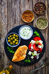 Seared chicken breast and Greek salad on wooden table
