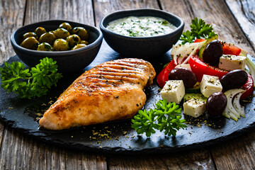 Seared chicken breast and Greek salad on wooden table
