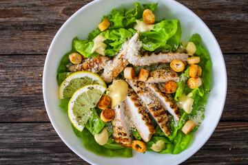 Caesar salad - fried chicken breast and vegetables on wooden table
