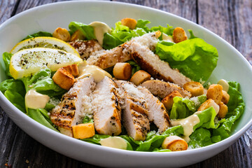 Caesar salad - fried chicken breast and vegetables on wooden table

