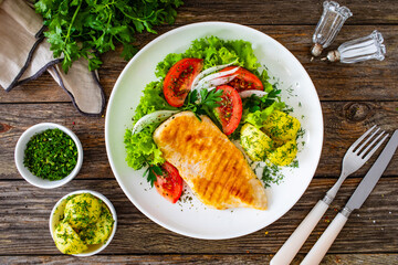 Grilled chicken breast, boiled potatoes and fresh vegetables on wooden table
