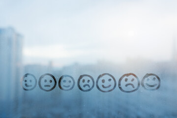 Foggy glass on window with drawn seven smile face with different emotions, concept photo of...