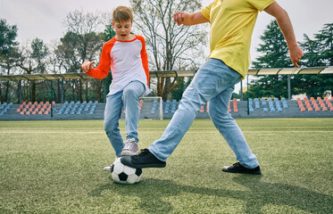 Obraz premium Father and Son play football on stadium outdoors, Happy family bonding, fun, players in soccer in dynamic action playing in sunny day, holidays time. 