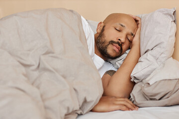 Portrait of adult black man sleeping in comfortable bed in cozy home