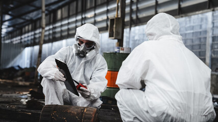 Workers wear protection suit checking chemical in old factory. Protecting Against Hazards and...