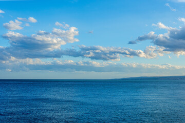 scenic blue seascape of sunset or sunrise above water with beautiful colorful evening clouds