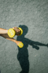 Crop sportswoman holding dumbbells