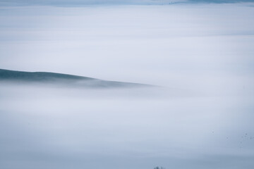 Mountains in a fog illuminated by rising sun. Autumn landscape with vivid sunlight. 
