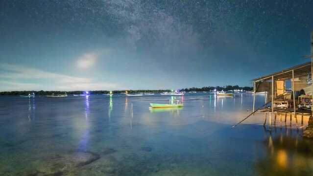 Captivating footage captures the beauty of a tropical night by the seaside, with clear waters, a mesmerizing Milky Way, and the moon's luminance