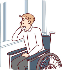 Unhappy handicapped man sits in wheelchair and sadly looks out window suffering from loneliness