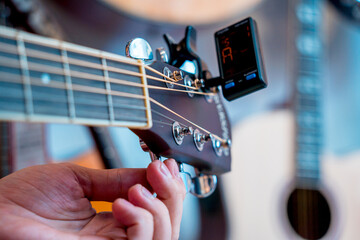 Young musician tuning a classical guitar in a guitar shop