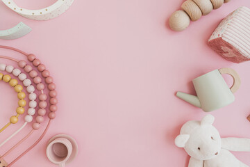 Baby kids toys background. Teddy bear, wooden educational stacking rainbow, toy kitchenware on pastel pink background. Top view, flat lay mock up with blank empty copy space