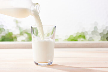 牛乳をガラスコップに注ぐ、健康的で爽やかな光 - obrazy, fototapety, plakaty