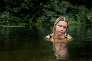 Portrait of a young beautiful blonde girl in the river.