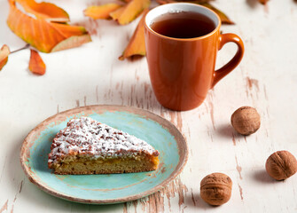 Baked pie served with hot tea on table with dried leaves and walnuts .autumn composition
