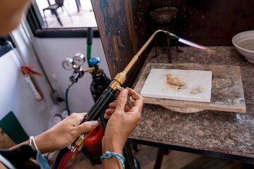 Obraz premium Jeweler using a burner to shape a piece in a workshop