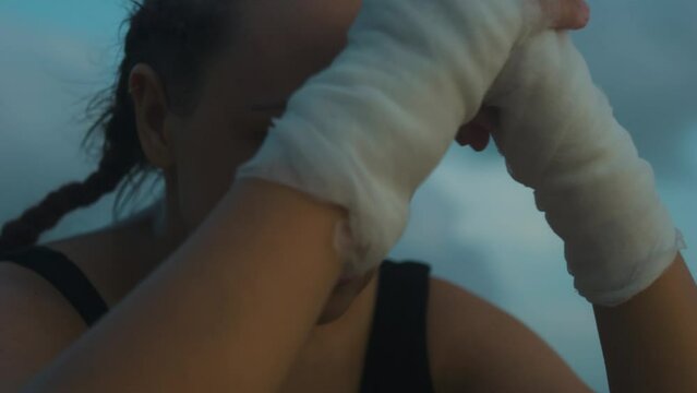 Sad female boxer MMA fighter on beach looks into distance with head in hands.