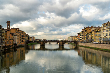 A picturesque view of Ponte Vecchio, the oldest bridge in Florence, with the River Arno flowing beneath it