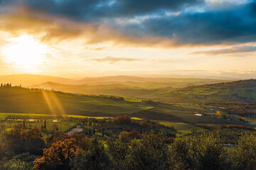 picturesque rolling hills of Tuscany are captured during a breathtaking sunset, with the sun's warm...