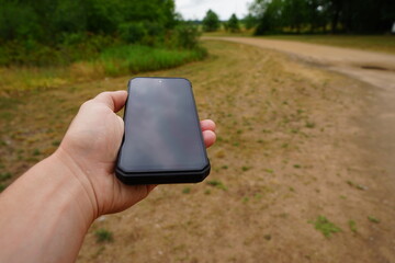 A black blank-screen smartphone is being held