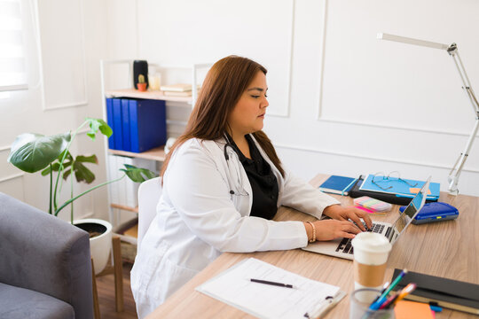 Hispanic plus size female doctor working in her office - Powered by Adobe