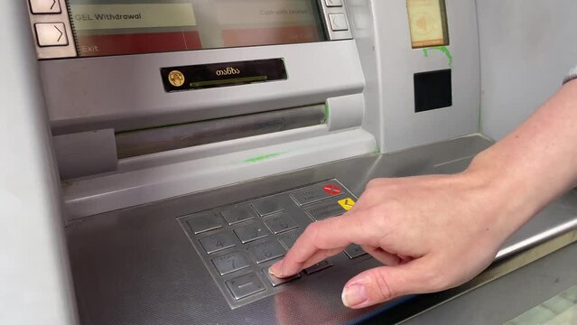woman typing pin on keypad atm to withdraw money, bank cash machine