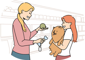 Fototapeta premium Girl with dog stands in ZOO shop near woman seller offering to buy toy bone for pet