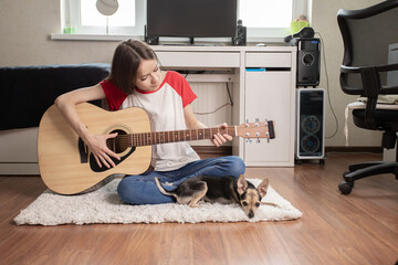 teenager girl playing guitar at home in teen room, Musical talent, guitar lessons, a small dog lies nearby