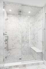 A walk-in shower with wavy marble pattern tiles, chrome faucets, and a built-in bench.