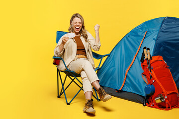 Full body happy young woman sit near bag with stuff tent hold credit bank card do winner gesture...