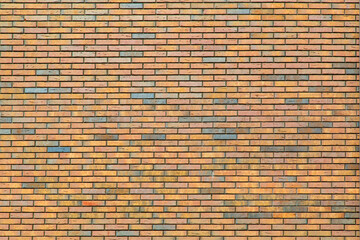 A large section of a wall of red bricks with splashes of gray, stacked in a vintage style.