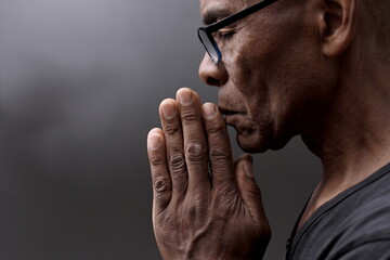 black man praying to god with hands together Caribbean man praying stock photo	