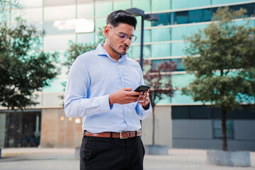 Serious business man, salesman, manager or broker having a serious conversation using his mobile phone or reading text messages. Handsome and focussed businessperson browsing internet with a cellphone