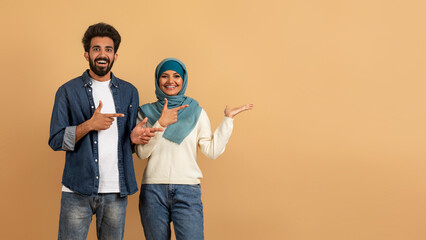 Check This. Cheerful Muslim Couple Pointing At Empty Palm