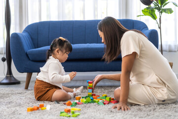 Naklejka premium Portrait of enjoy happy love asian family mother with little asian girl smiling activity learn and skill brain play toy build wooden block board education game, children development at home