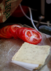 Tomato slices and cheese slices ready to be put on a burger, rustic kitchen, home cooking